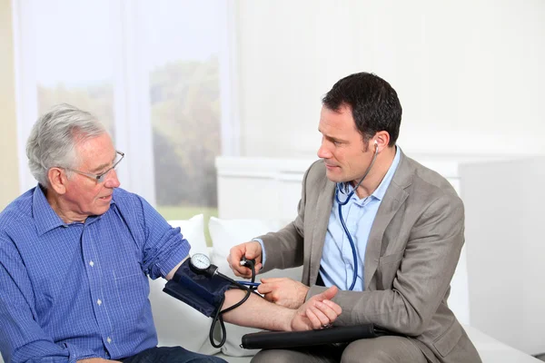Doctor taking old man\'s blood pressure