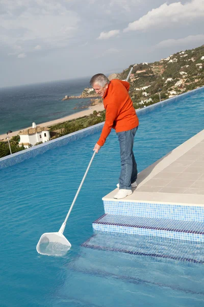 Senior couple cleaning swimming pool