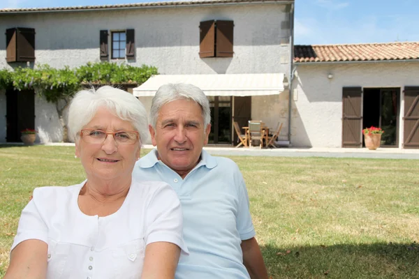 Senior couple sitting in front of a house
