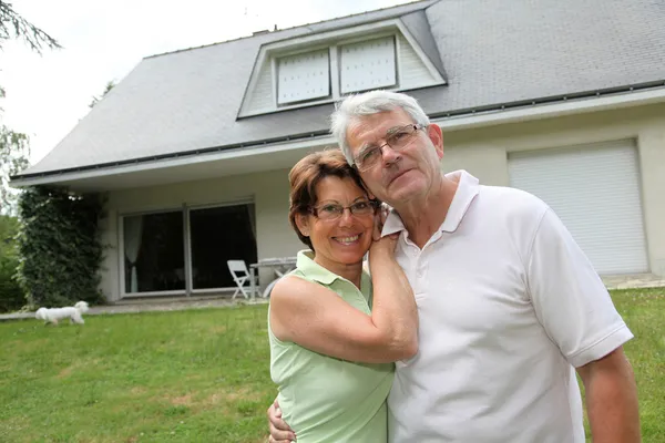Senior couple standing in front of a house