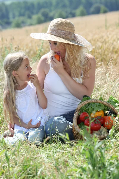 Mother and little girl eating fruits