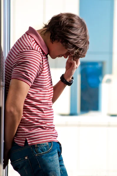 Depressed young man standing against window in the background