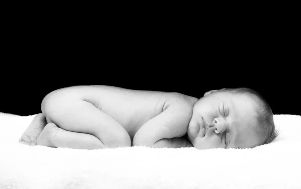 Newborn sleeping child on white blanket.