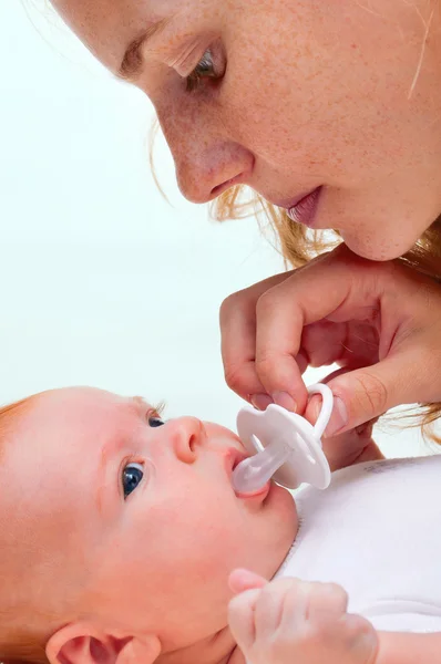 Young mother trying to give baby`s dummy to her newborn baby
