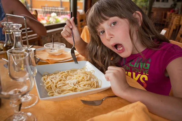 Girl eats pasta in italian restaurant