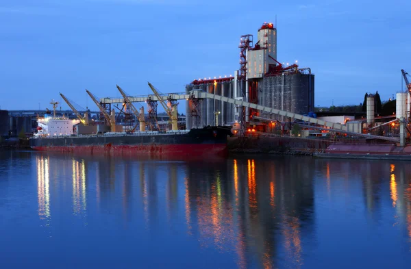 Grain elevators & cargo ship at dusk.