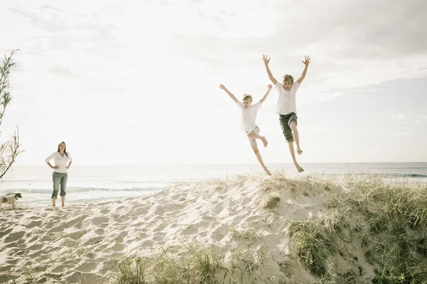 Boys jumping of a sand dune at the beach