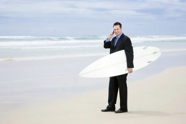 Business man in suit walking with surfboard on the beach