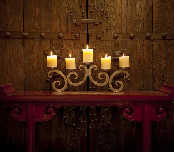 Candles burning on table in front of old rustic door
