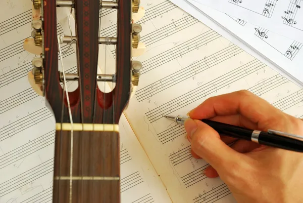 Guitar with hand composing music on manuscript