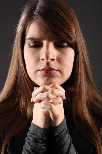 Religious woman eyes closed hands clasped praying