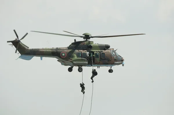 Two soldiers hanging from a helicopter