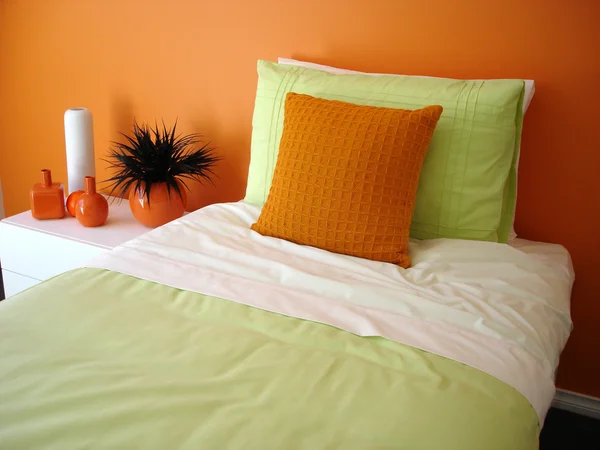 Vibrantly orange bedroom with green bedlinen