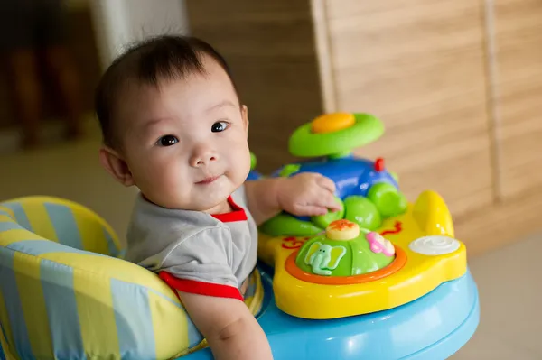 6 month old Asian baby girl plays sitting in a walker