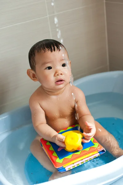 8 month old Asian baby girl having fun playing with water during her bath
