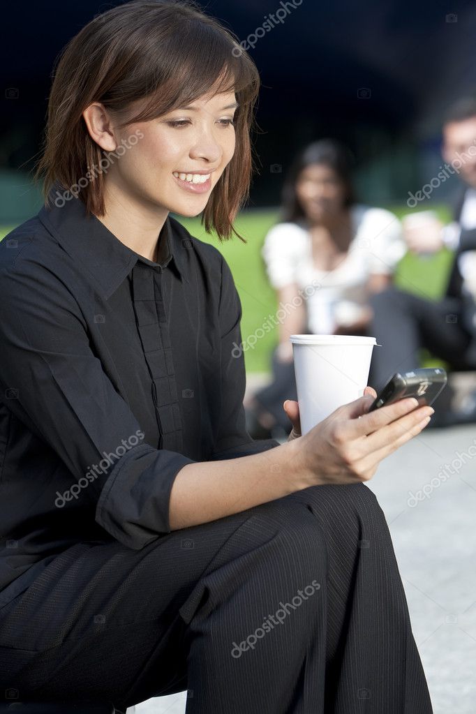 A beautiful young Eurasian woman with a wonderful smile texting on her cell