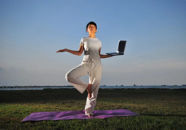 Asian chinese lady holding a laptop with yoga stance