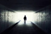 Silhueta do homem a andar no túnel. luz no fim do túnel — Fotografia Stock 