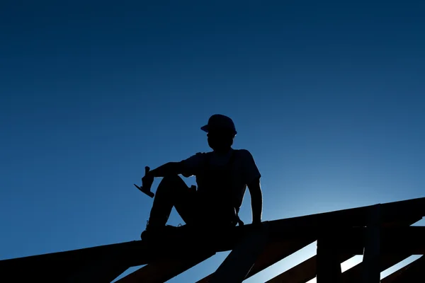 Builder or carpenter resting on top of roof structure