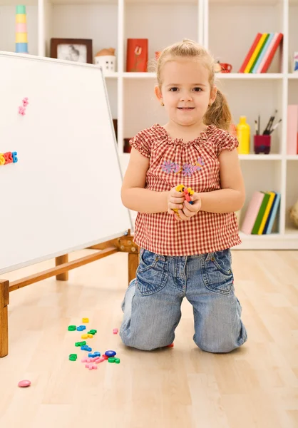 Little girl playing with magnetic board