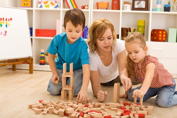 Woman and kids playing with wooden blocks