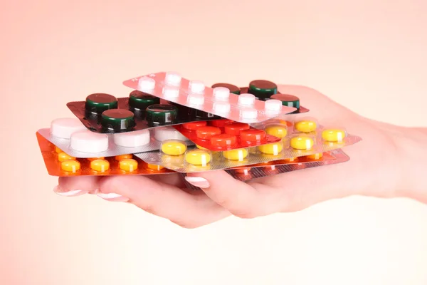 Woman hand with a lot of pills on red background