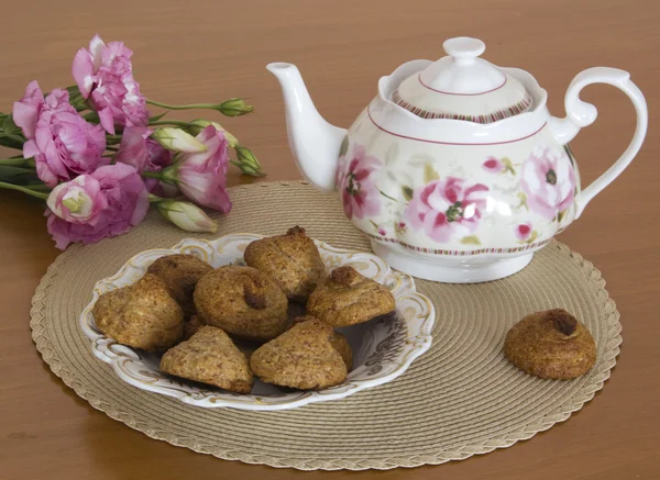 Fıstık çerez çaydanlık ve masanın üzerine çiçek — Stok fotoğraf