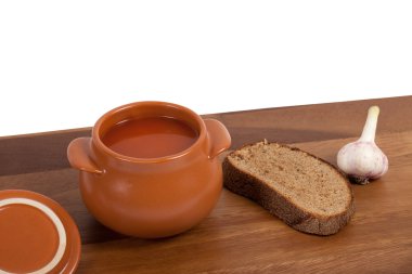 Soup in clay pot on wooden table clipart