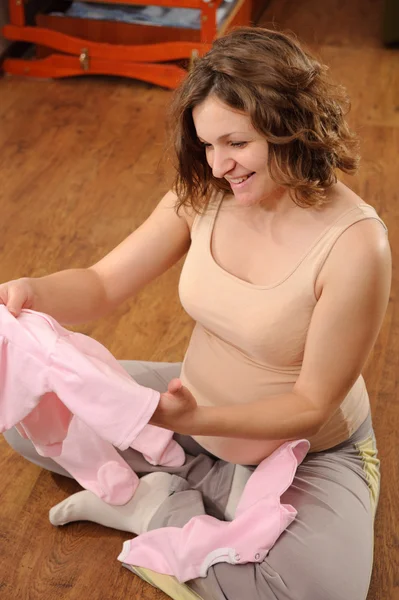 Zwangere vrouw met baby's kleding — Stockfoto