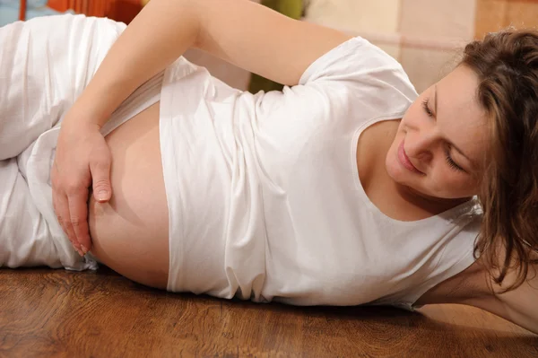 Sorrindo grávida deitada no chão — Fotografia de Stock
