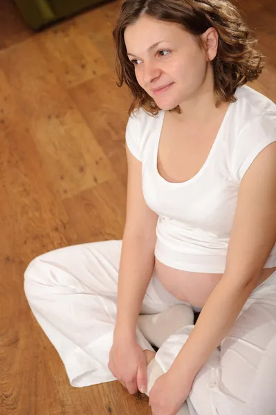 Беременная женщина сидит на полу — стоковое фото