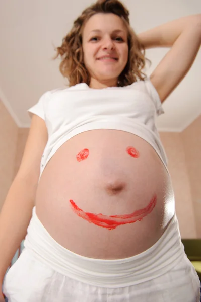 Молодая беременная с раскрашенным знаком улыбки — стоковое фото
