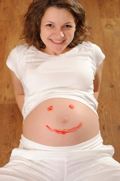Junge Schwangere mit aufgemaltem Lächeln — Stockfoto