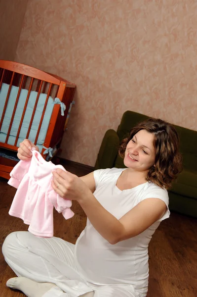 Gravid kvinna med barnets kläder — Stockfoto