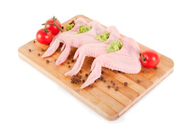 Raw chicken wings with condiments on chopping board clipart