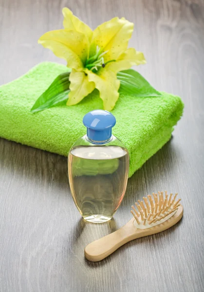 Fles haarborstel handdoek en bloem — Stockfoto