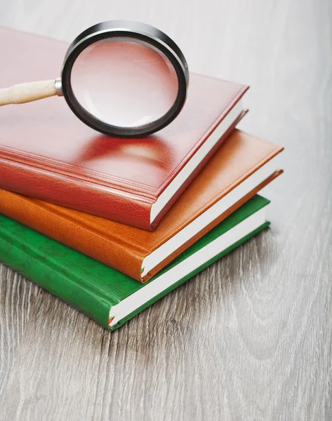 Notebooks and magnifier on wooden background — Stock Photo, Image