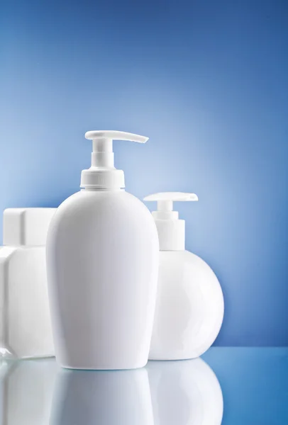 Botellas blancas para el cuidado de la piel sobre fondo azul — Foto de Stock