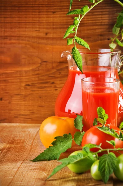 Jarro e vidro com suco de tomate e tomates — Fotografia de Stock