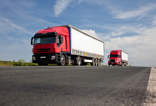 Dvě červené nákladních automobilů na silnici — Stock fotografie