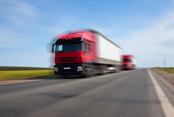 Dois caminhões vermelhos movimento turvo — Fotografia de Stock