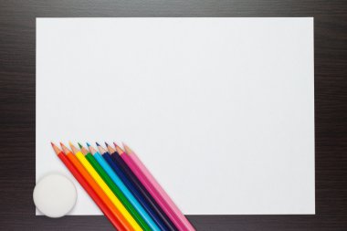 Blank sheet of paper on the table with colorful pencils and rubb clipart