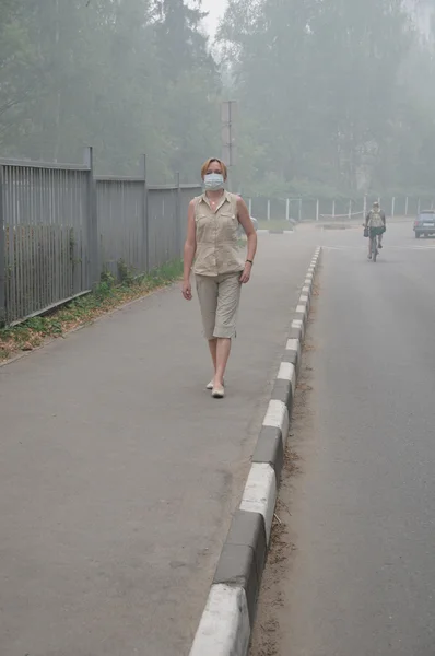 Kvinnan promenader i tunga smog — Stockfoto