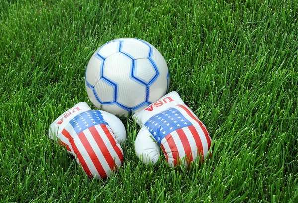 Luvas de boxe e bola de futebol no gramado verde — Fotografia de Stock