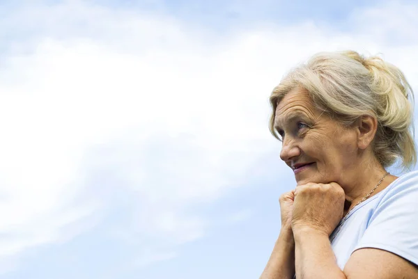 Ältere Frau steht am Himmel — Stockfoto