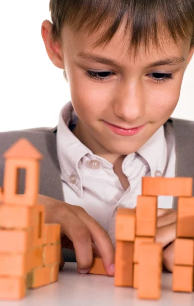 Handsome boy builds a toy castle — Stock Photo, Image