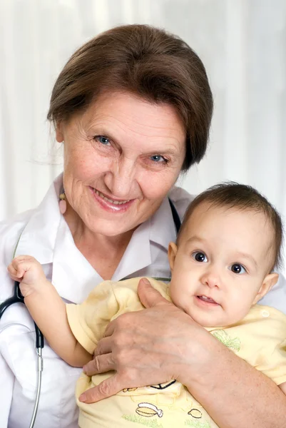 Elderly doctor holding a newborn — Stock Photo, Image