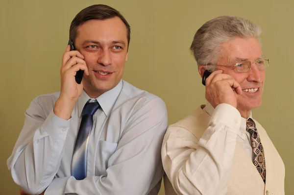 Two adult businessman standing and talking on the phone — Stock Photo, Image