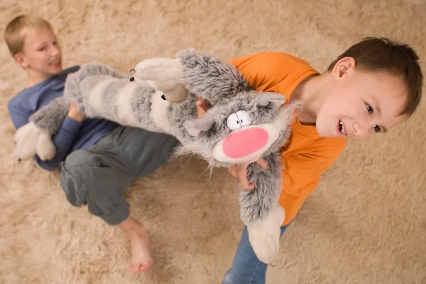 Två barn med en leksak katt på den mjuka mattan — Stockfoto