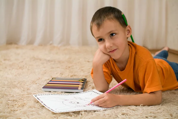 Młody dzieciak z kredki na dywanie. — Zdjęcie stockowe